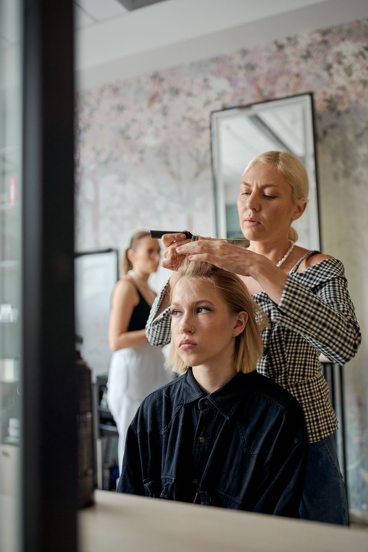 Estilista peinando el cabello de una clienta frente al espejo en un salón de belleza