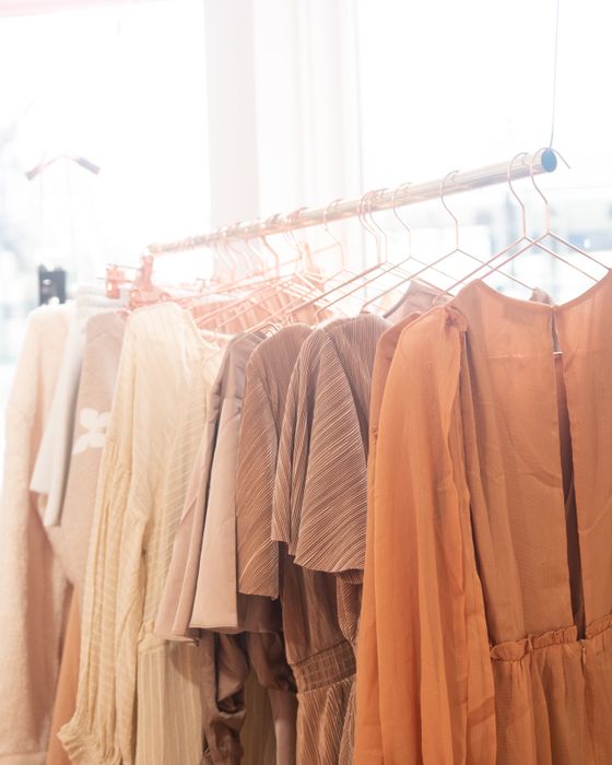 Ropa colgada en percheros dentro de una tienda de ropa iluminada