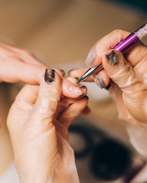 Manicurista aplicando esmalte en una sesión de uñas